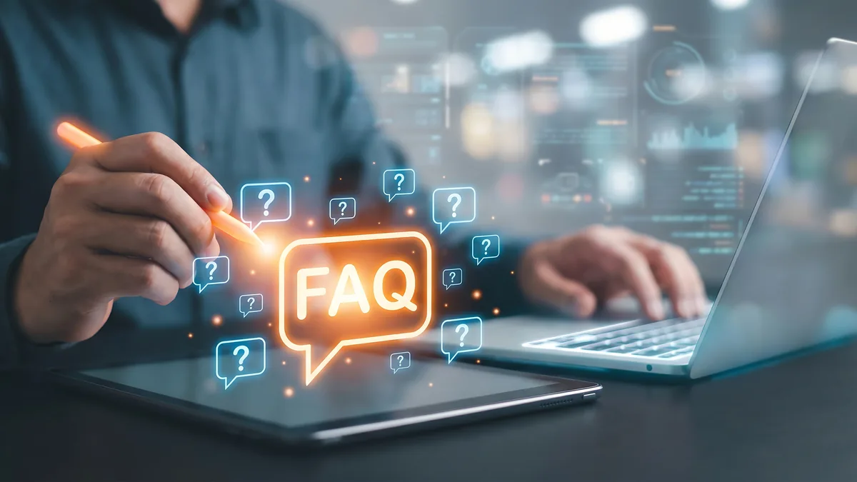 Leuchtende FAQ-Sprechblase und blaue Fragezeichen-Symbole über Tablet und Laptop, an dem eine Person arbeitet