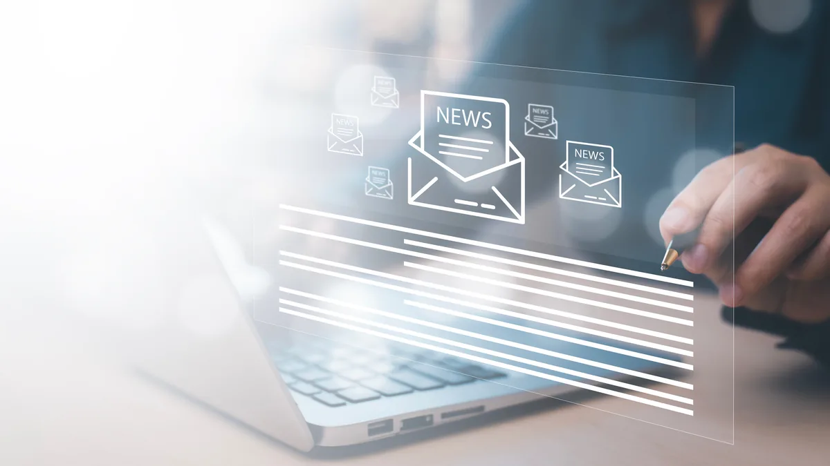 Aufgeklappter Laptop auf einem Schreibtisch, darüber schweben transparente Bildschirmflächen mit Briefumschlag-Symbolen und dem Schriftzug NEWS; rechts hält eine Hand einen Stift