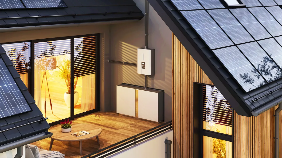 Batteriespeicher und Wechselrichter an der Außenwand eines Einfamilienhauses mit Photovoltaikanlage auf dem Dach