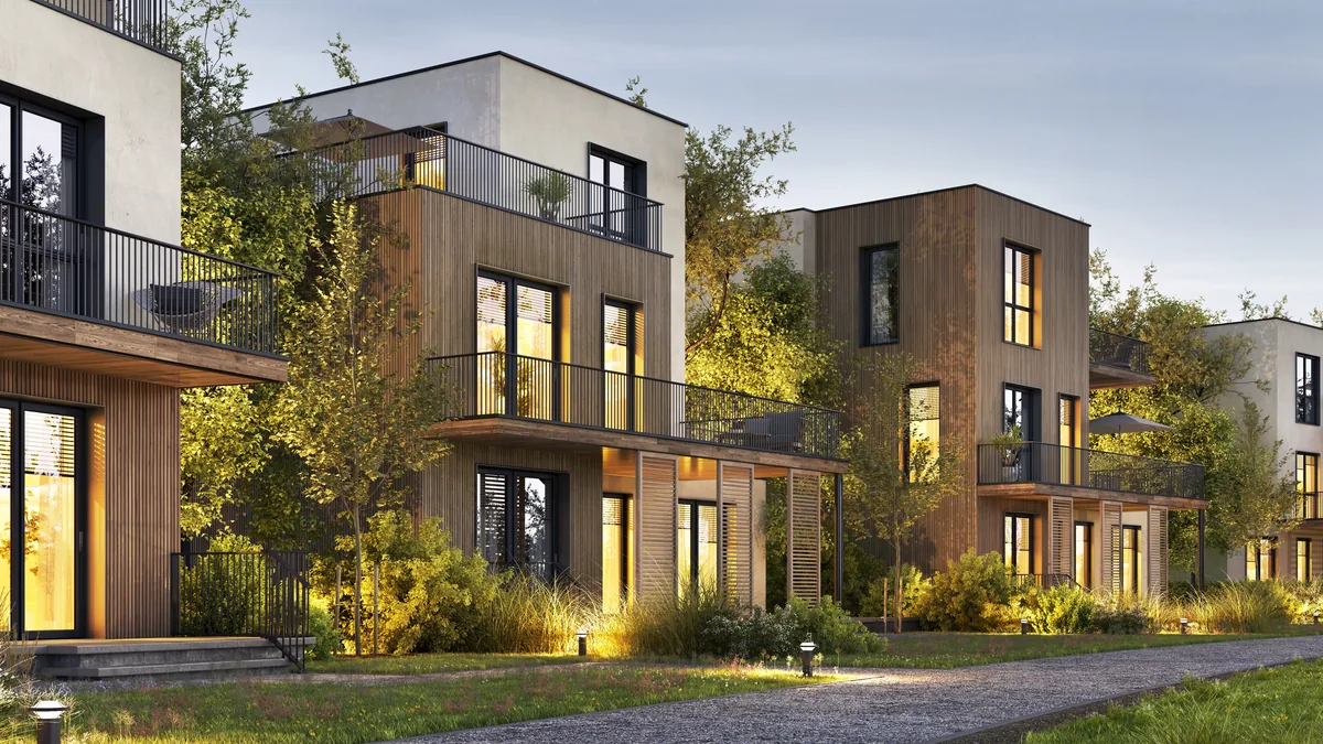 Moderne Mehrfamilienhäuser mit Holzfassaden und beleuchteten Fenstern in der Abenddämmerung
